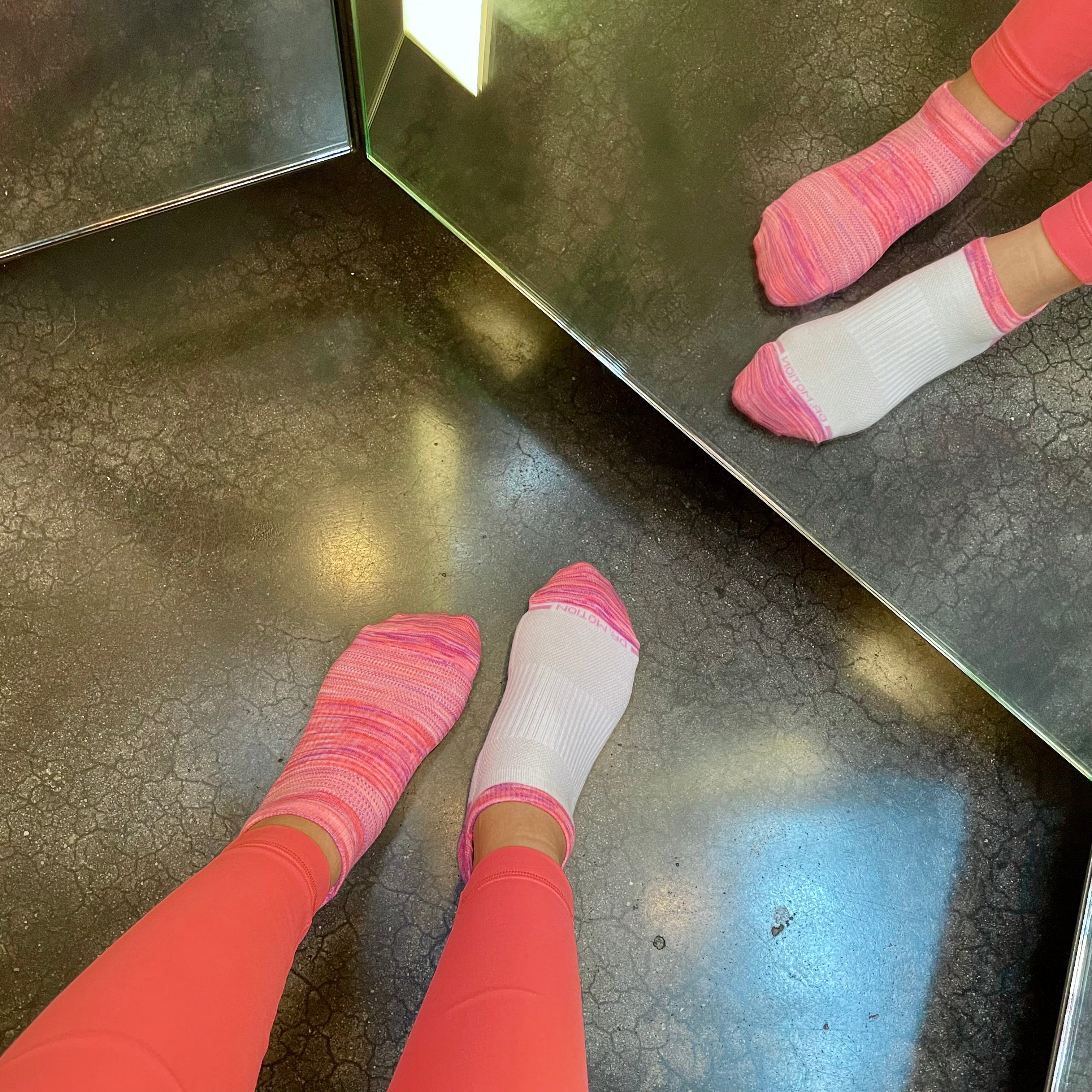 Ankle compression socks in pink and white, worn with pink leggings, reflected in a mirror.