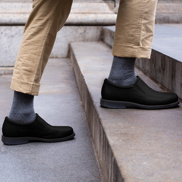 Knee-high compression socks with a pin dot pattern worn with black slip-on shoes and khaki pants on stone steps.