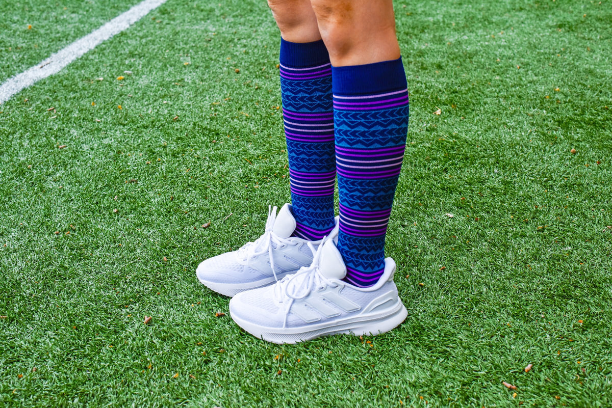 Navy Soft Aztec Dr. Motion sports compression socks worn with white sneakers on green turf