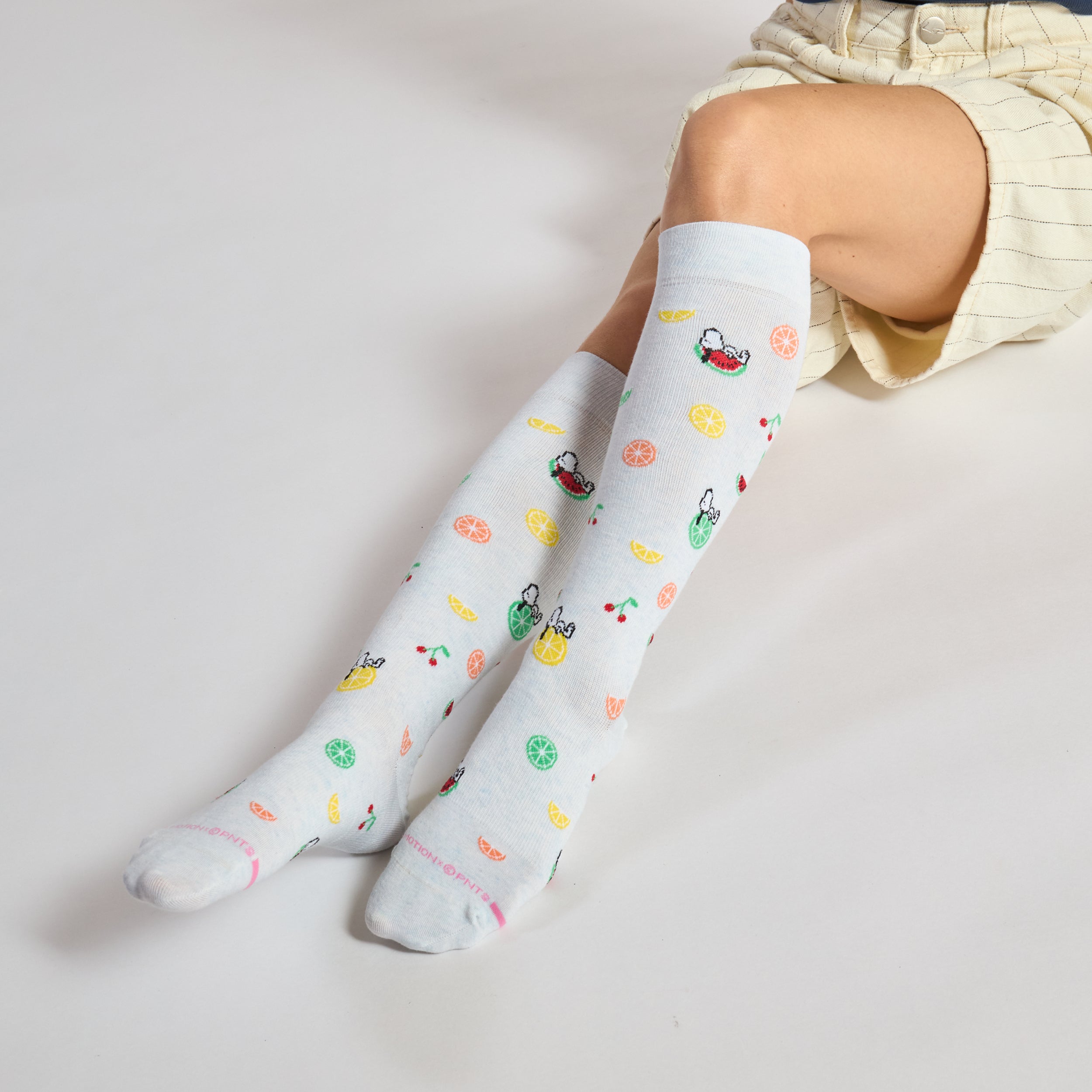 Knee-high compression socks with a light blue background and colorful fruit patterns.